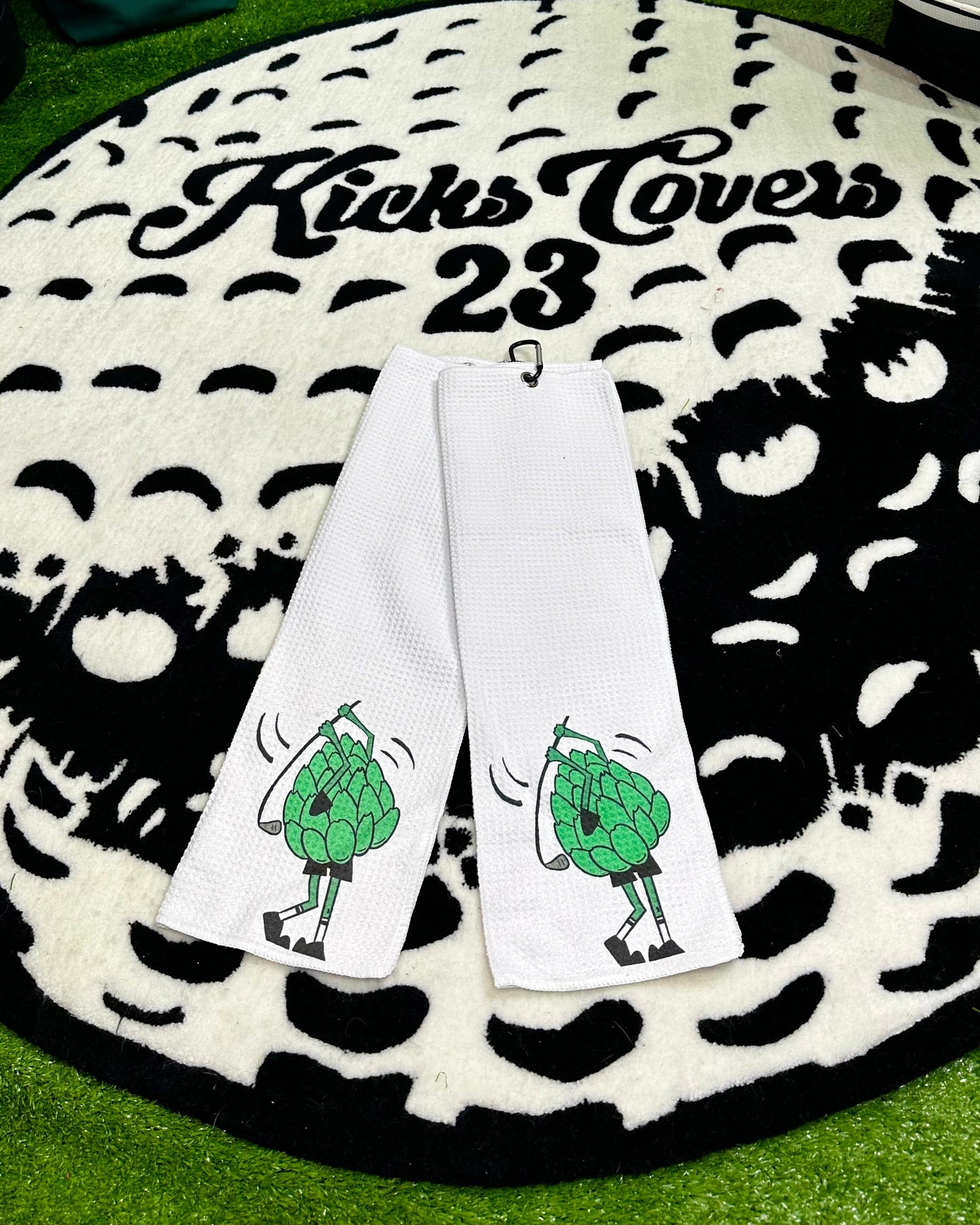 Towel with cartoon characters on a branded mat, with 'Kicks Covers' branding visible.