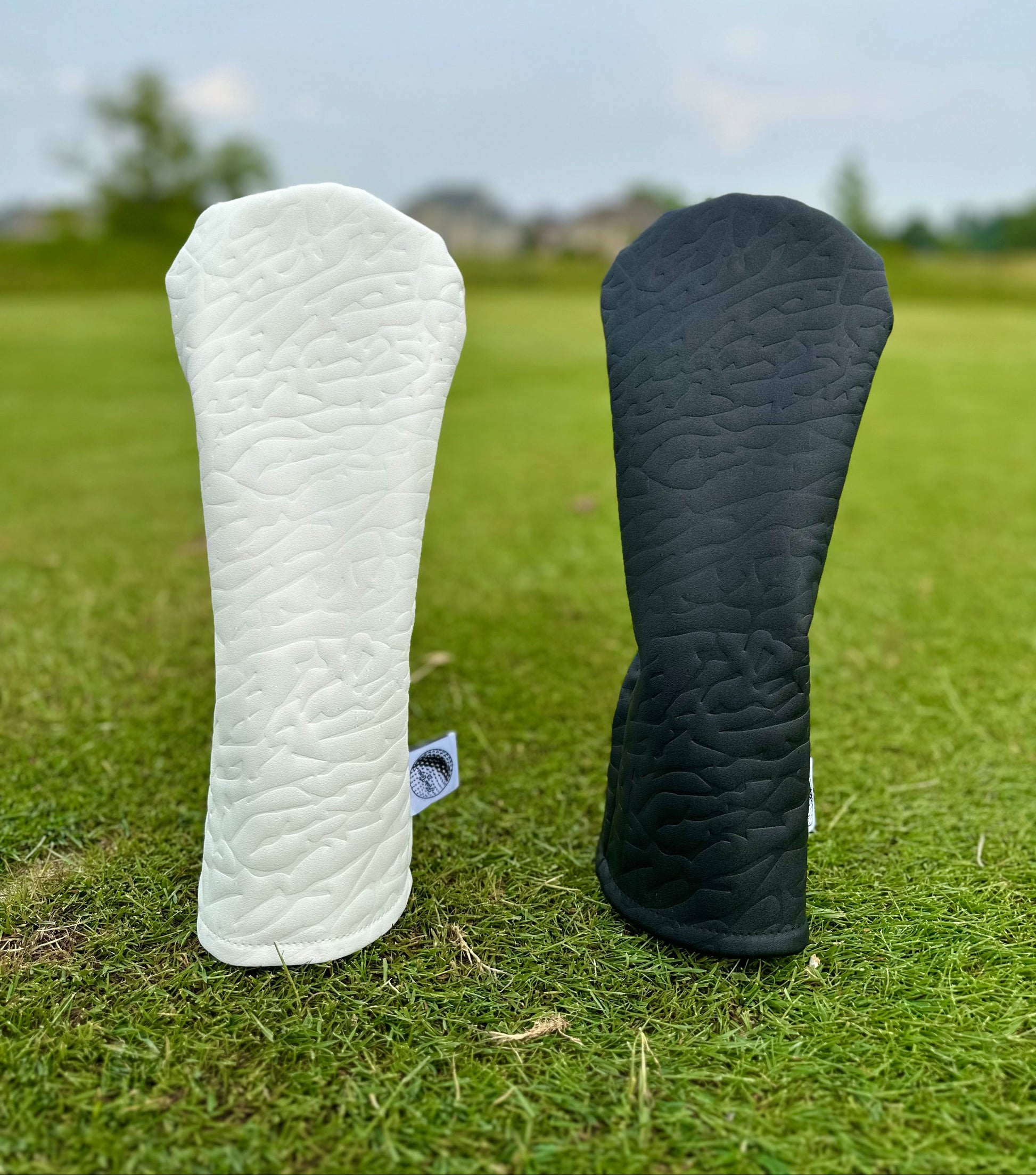 White and black golf club headcovers on a grassy background