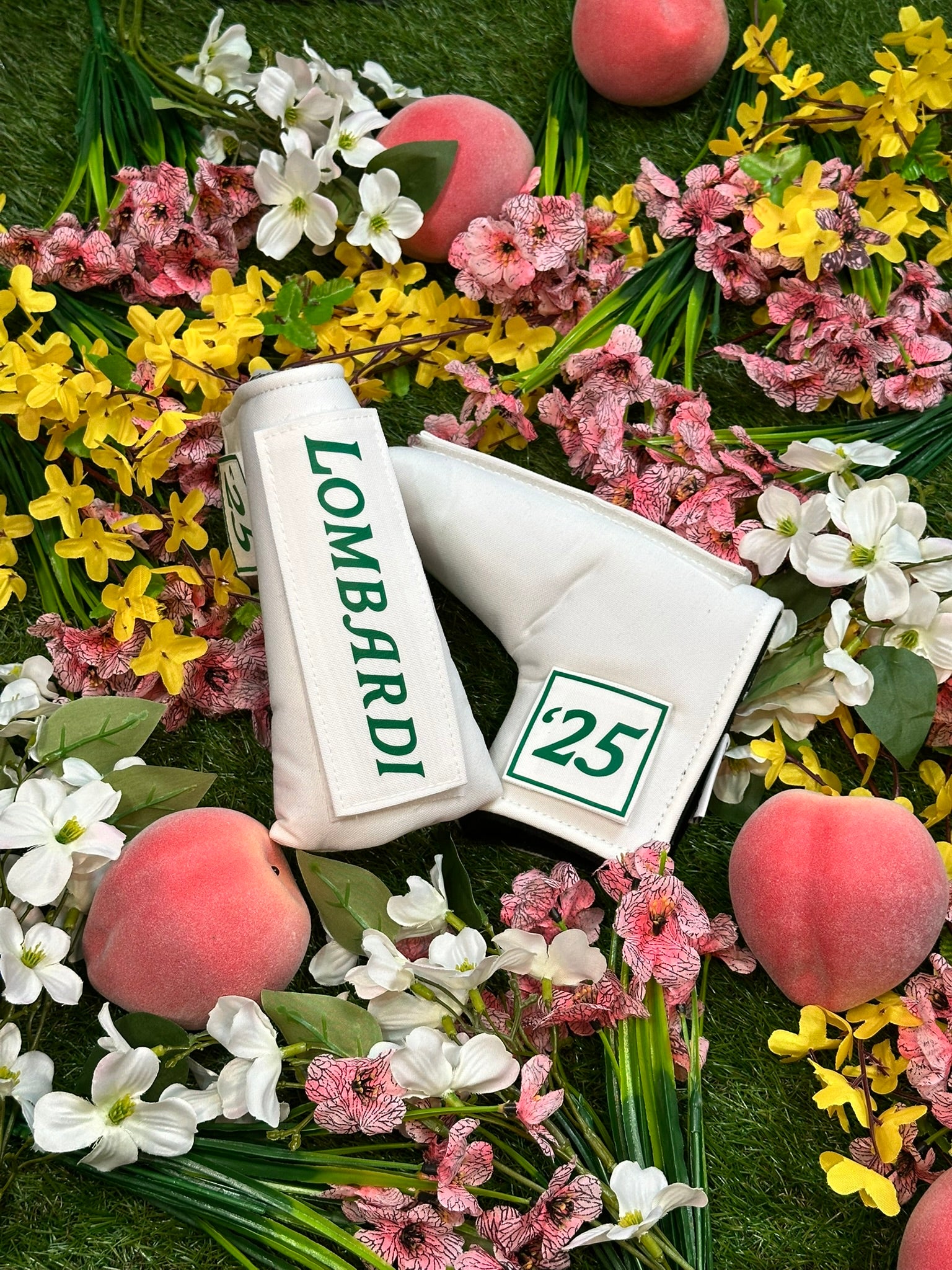 Masters name tape putter cover surrounded by flowers and fruits on a green background