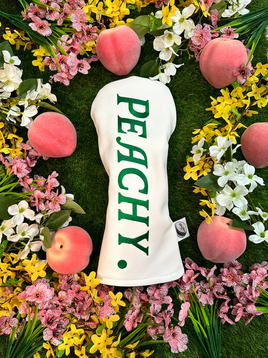 White golf club head cover with 'PEACHY' text surrounded by peaches and flowers