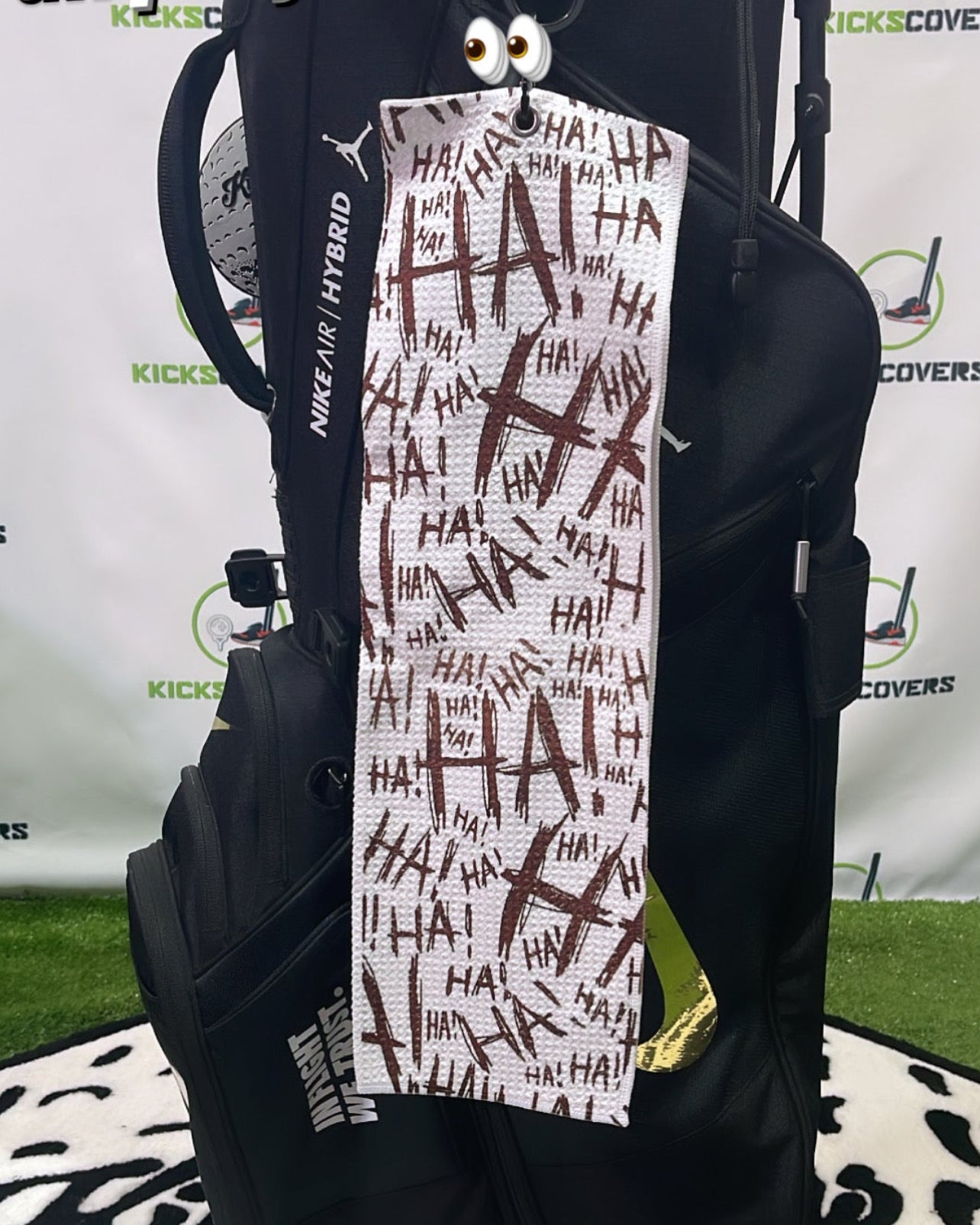 Joker themed towel with text on a black bag against a branded backdrop