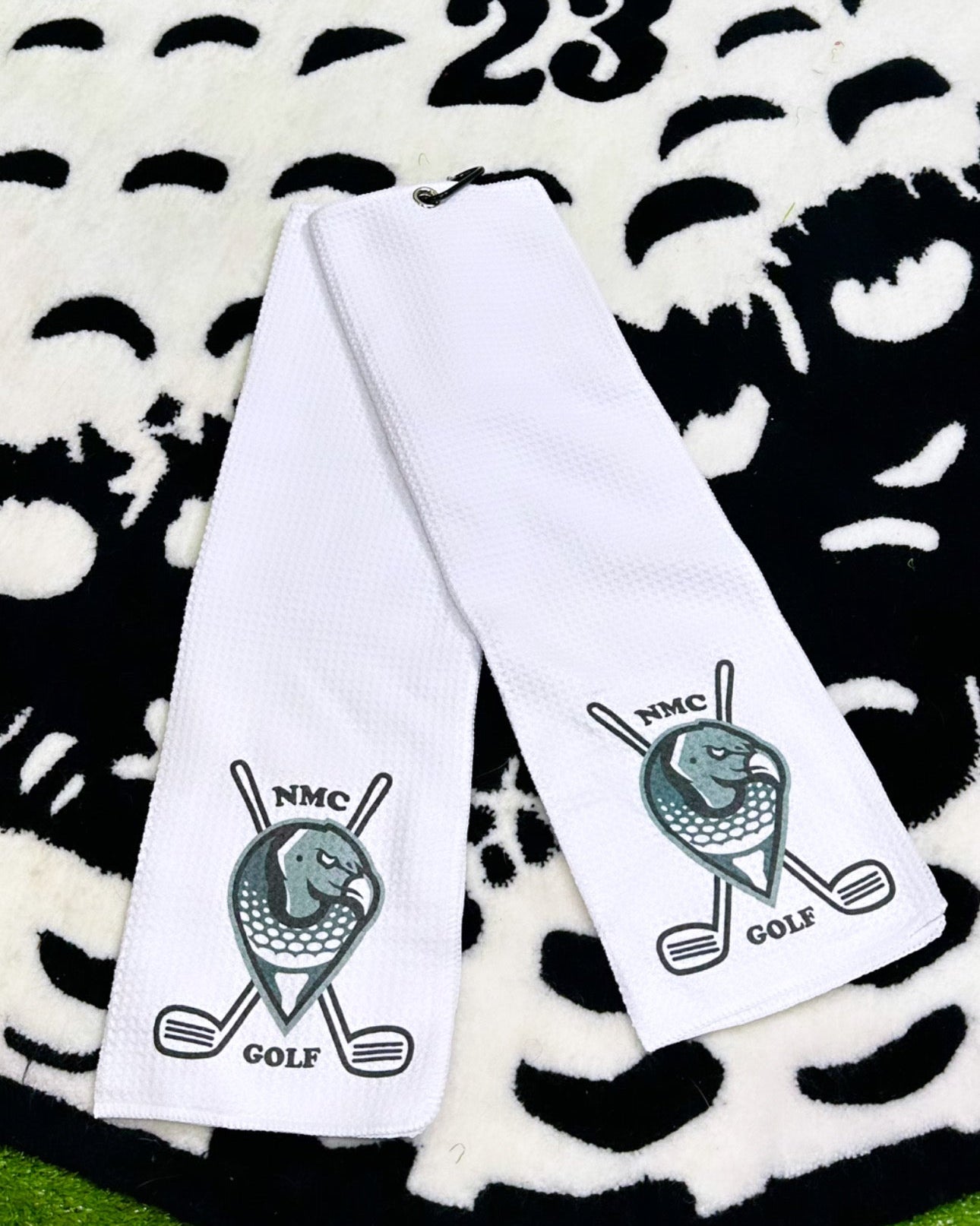 Two white golf towels with logos on a patterned background with 'Kicks Towels 23' text.