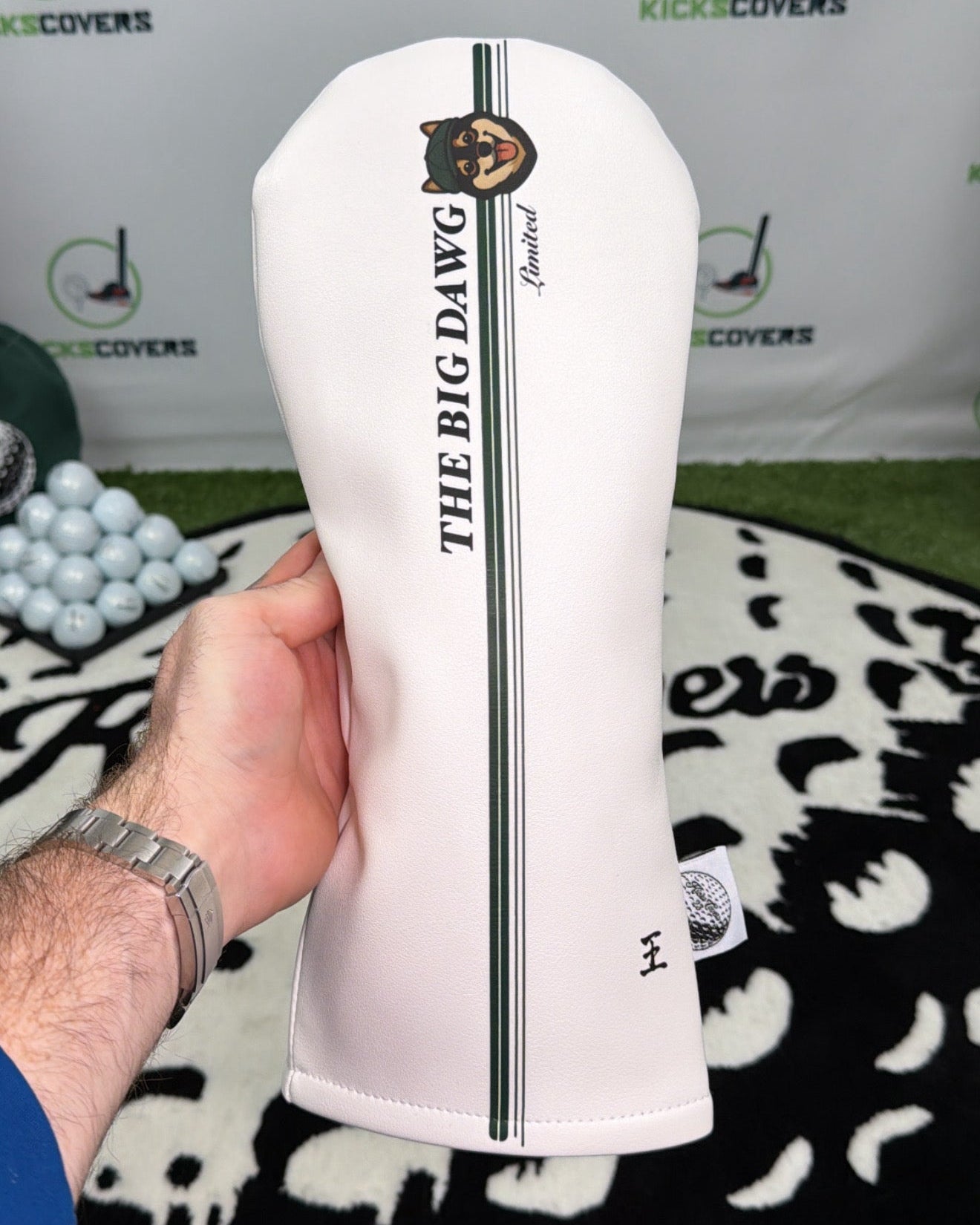 White golf head cover with 'The Big Dawg' branding held by a person against a branded backdrop.